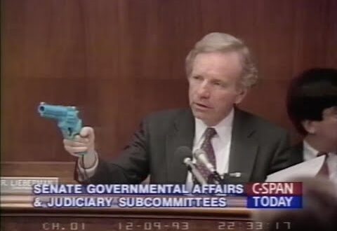 Senator Joe Lieberman holds up a light gun revolver from Konami's "Lethal Enforcers" game