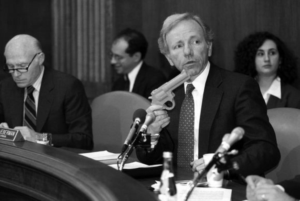 Man holding a toy gun at a meeting.