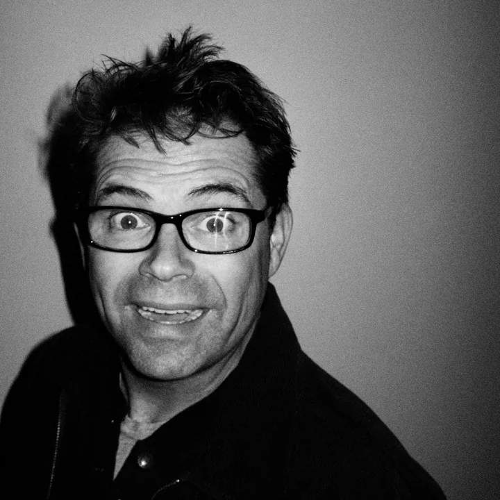 Comedian and Gex voice actor Dana Gould wearing glasses in a black-and-white portrait